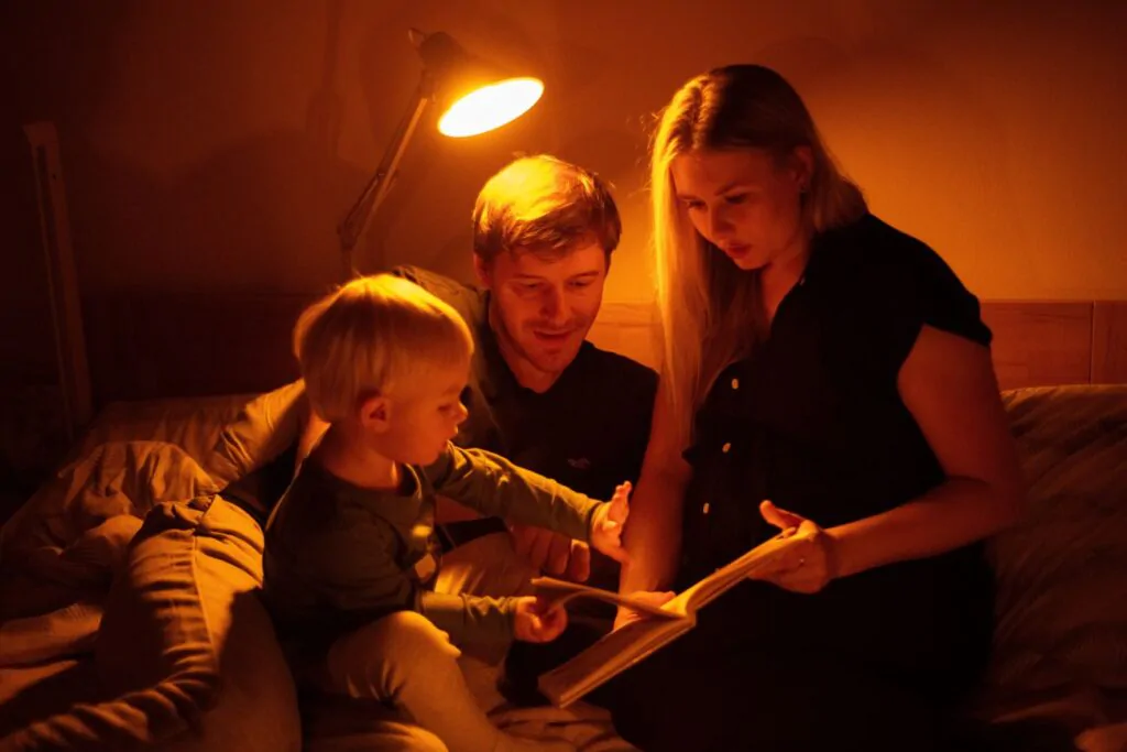 Rodina si čte a svítí při tom večerní žárovka ORANŽOVKA.