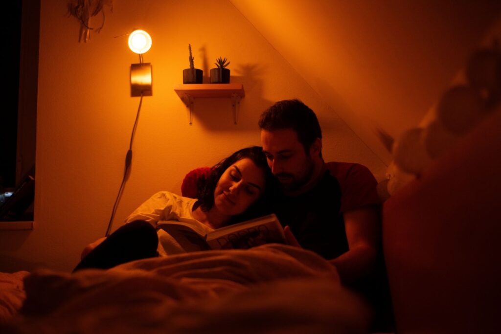 Pár si čte a svítí jim Žena pracuje a svítí jím večerní LED žárovka Oranžovka