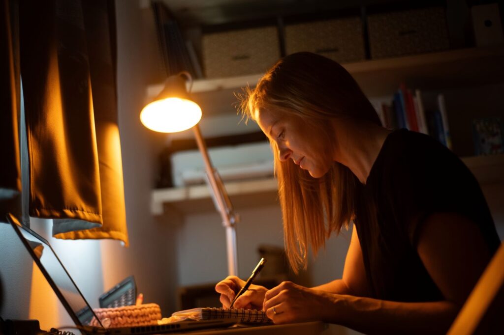 Žena pracuje a svítí jí večerní LED žárovka Oranžovka