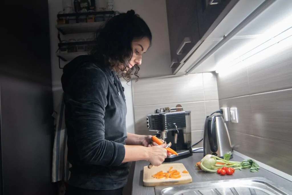 Světlo nad linkou v kuchyni a žena, která připravuje jídlo