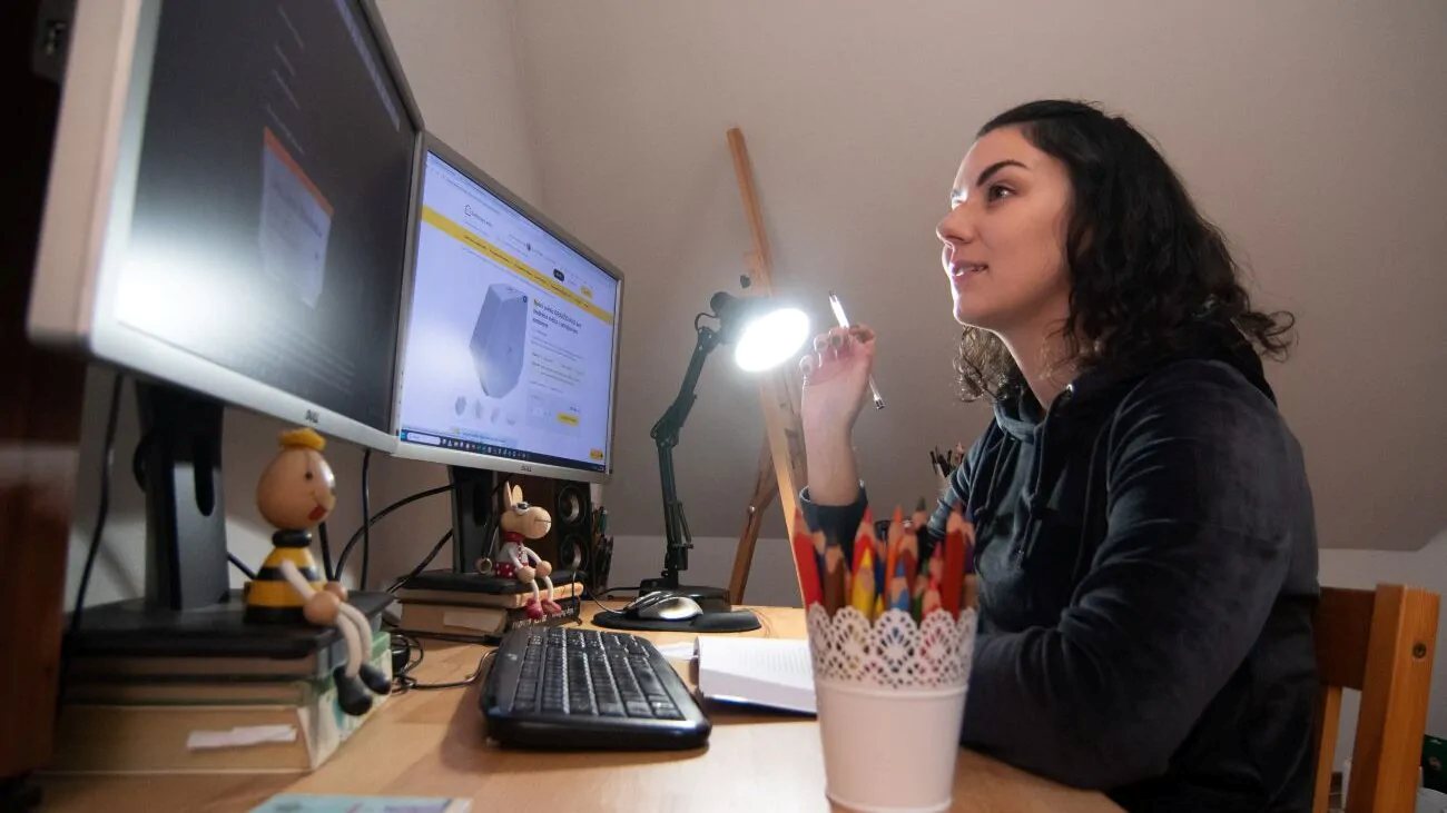 Mladá žena pracuje na počítači a u toho jí svítí Denní žárovka Oranžovka.