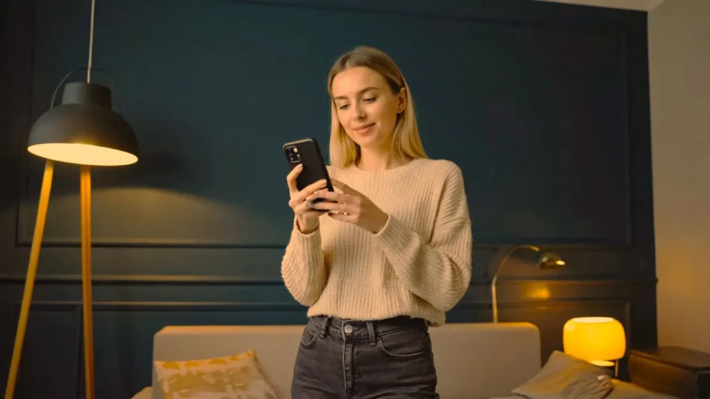 Žena je na mobilu a za ní svítí dvě lampy