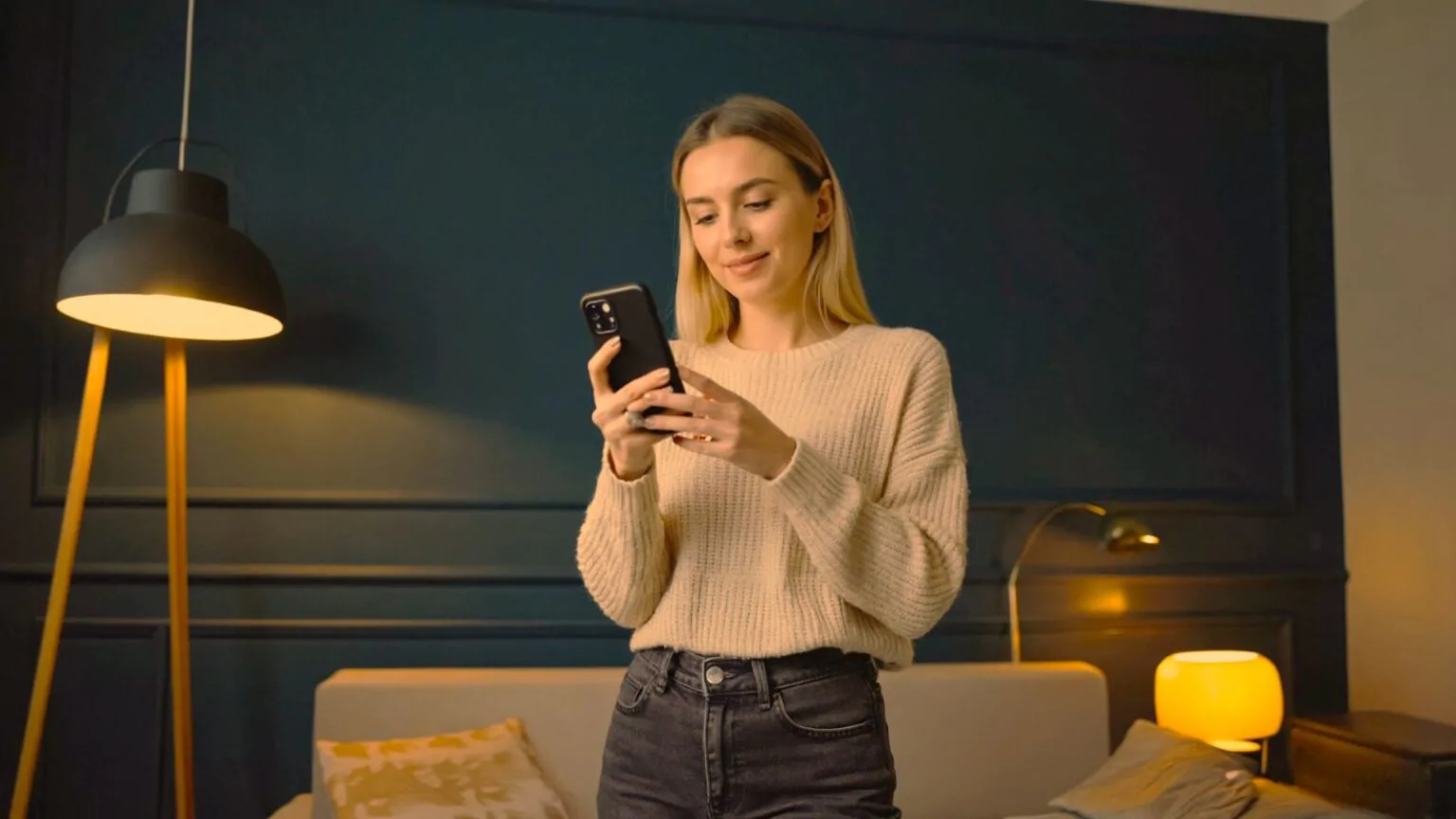 Žena je na mobilu a za ní svítí dvě lampy