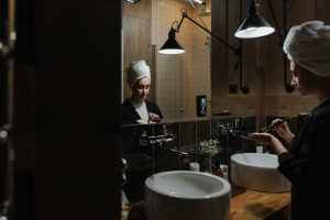 Žena si večer v koupelně u zrcadla čistí obličej